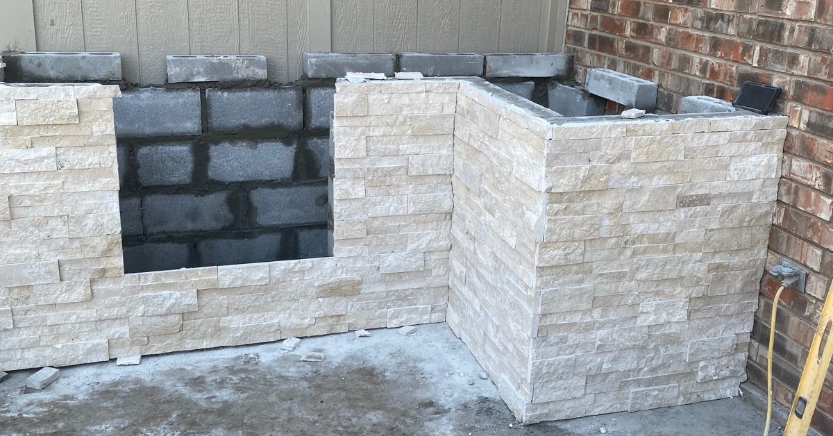 Picture of outdoor kitchen. Progress shows cinderblocks with outer layer of stonework application.