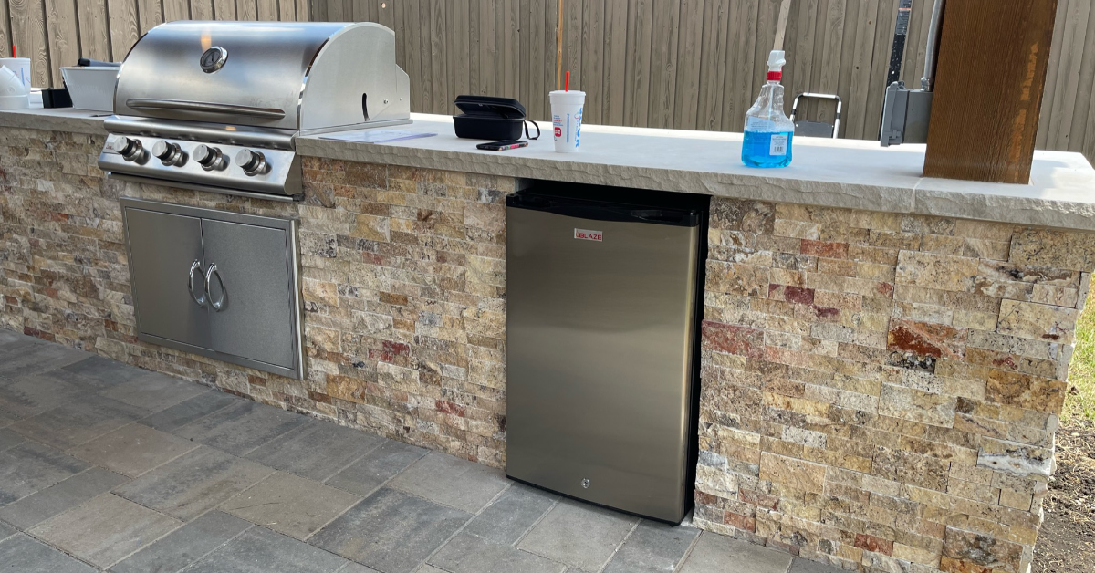Picture of outdoor kitchen complete with built-in gas grill & mini-fridge.