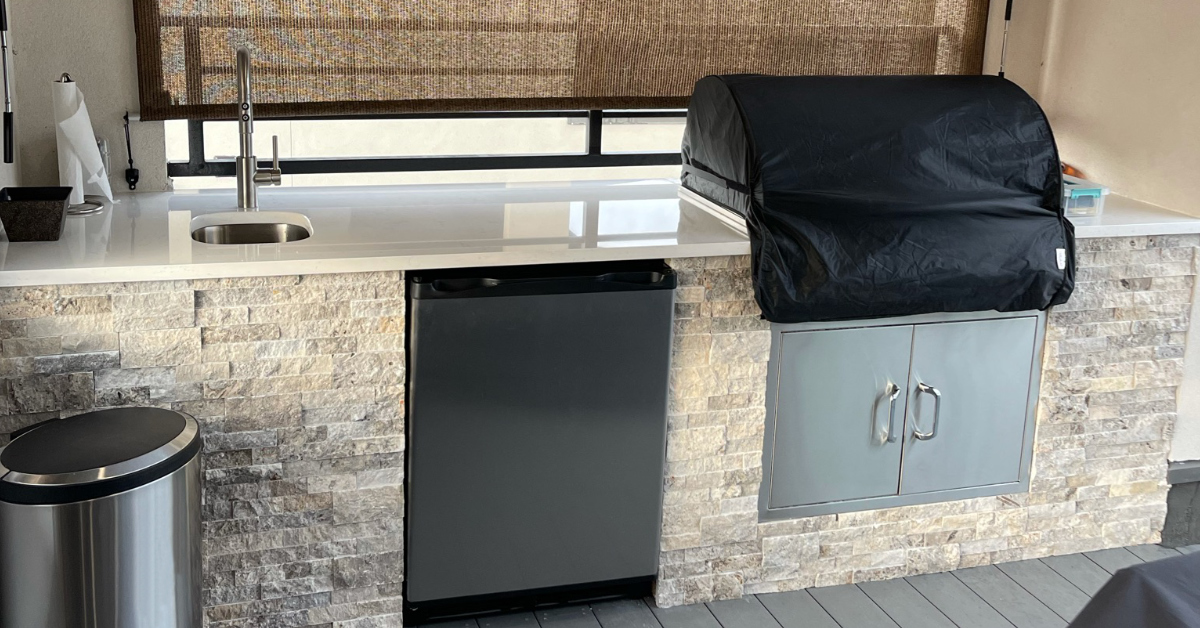 Picture of third floor balcony outdoor kitchen with quartz countertops, grill, sink, & mini fridge.