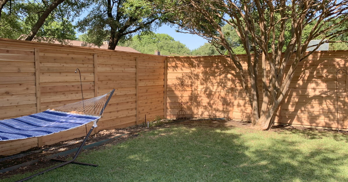 Board-on-board horizontal fence for privacy between multiple houses with a hammock.